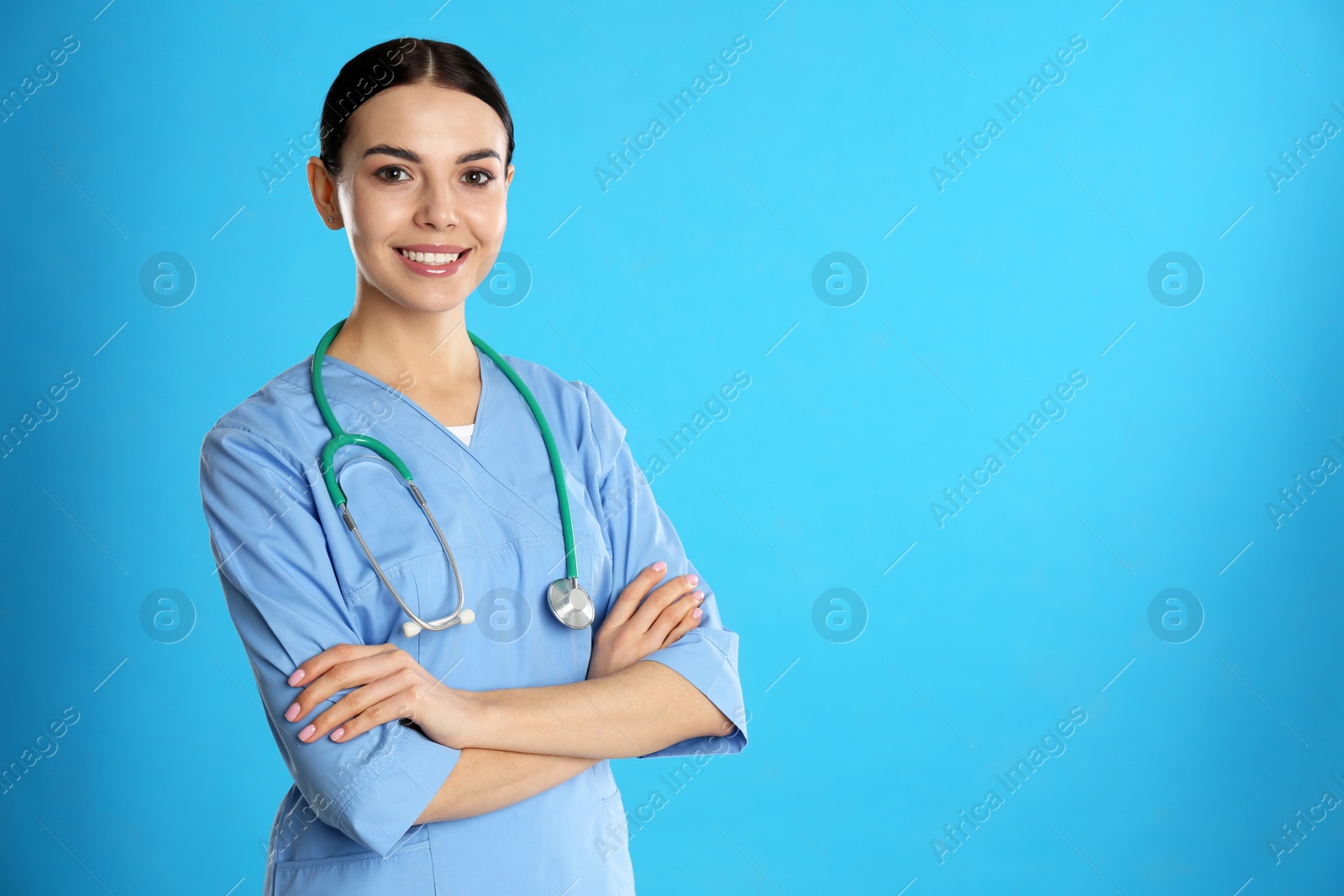 Photo of Portrait of young doctor with stethoscope on blue background. Space for text