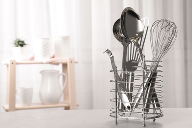 Holder with clean utensils on table in kitchen. Space for text