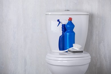 Photo of Different cleaning supplies on toilet bowl indoors, space for text