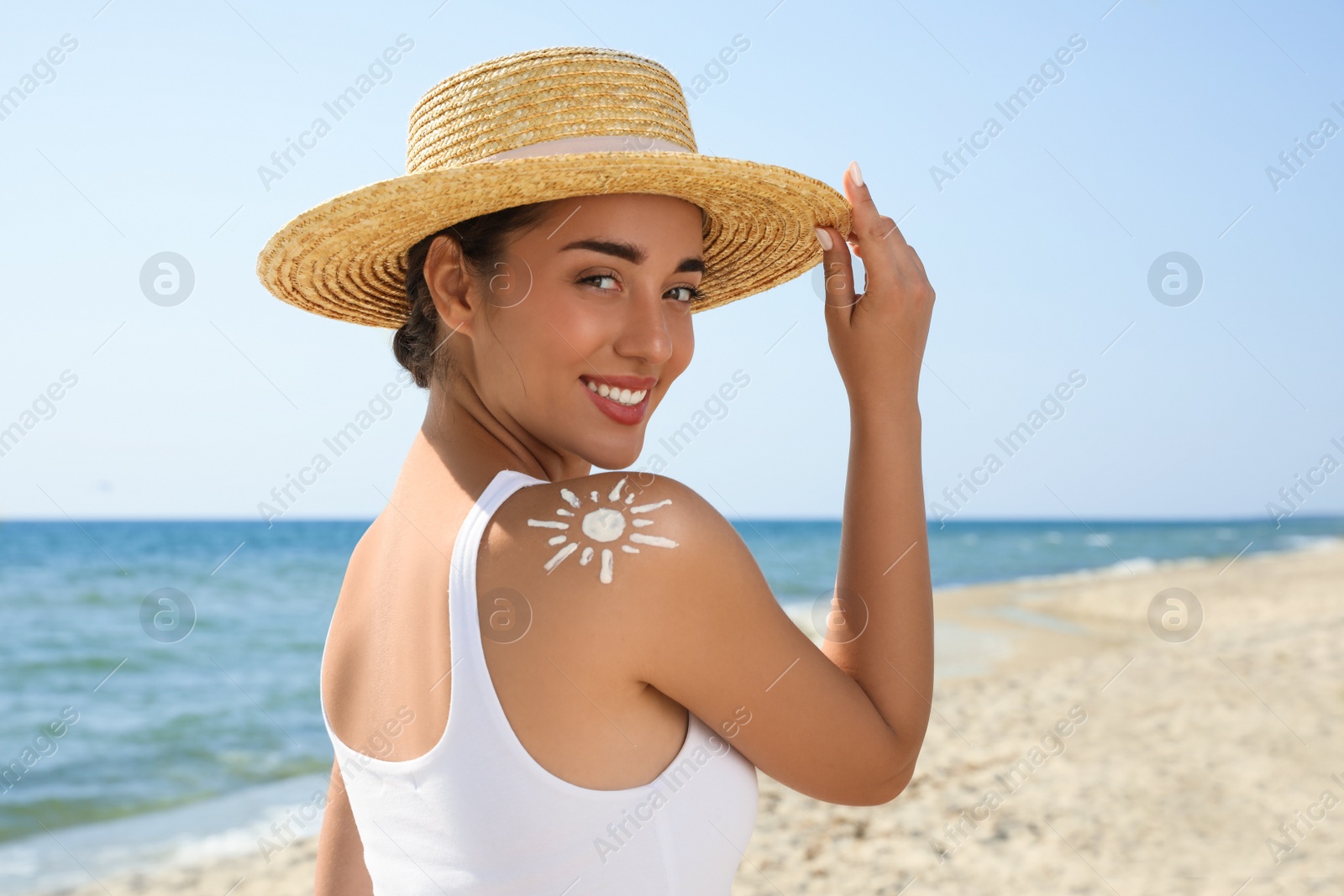 Photo of Beautiful young woman with sun protection cream on shoulder at beach