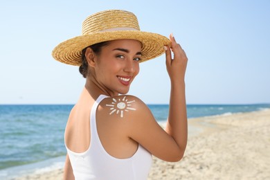Beautiful young woman with sun protection cream on shoulder at beach
