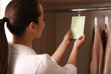 Photo of Young woman holding scented sachet in wardrobe