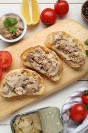 Photo of Tasty sandwiches with cod liver on white wooden table, flat lay