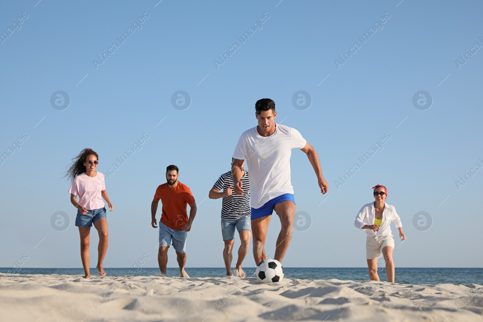 Photo of Group of friends playing football on beach