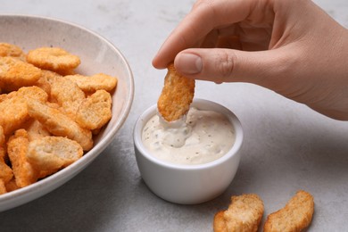 Photo of Woman dipping crispy rusk in sauce at light table, closeup