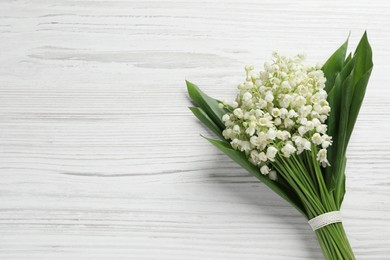 Photo of Beautiful lily of the valley bouquet on white wooden table, top view. Space for text