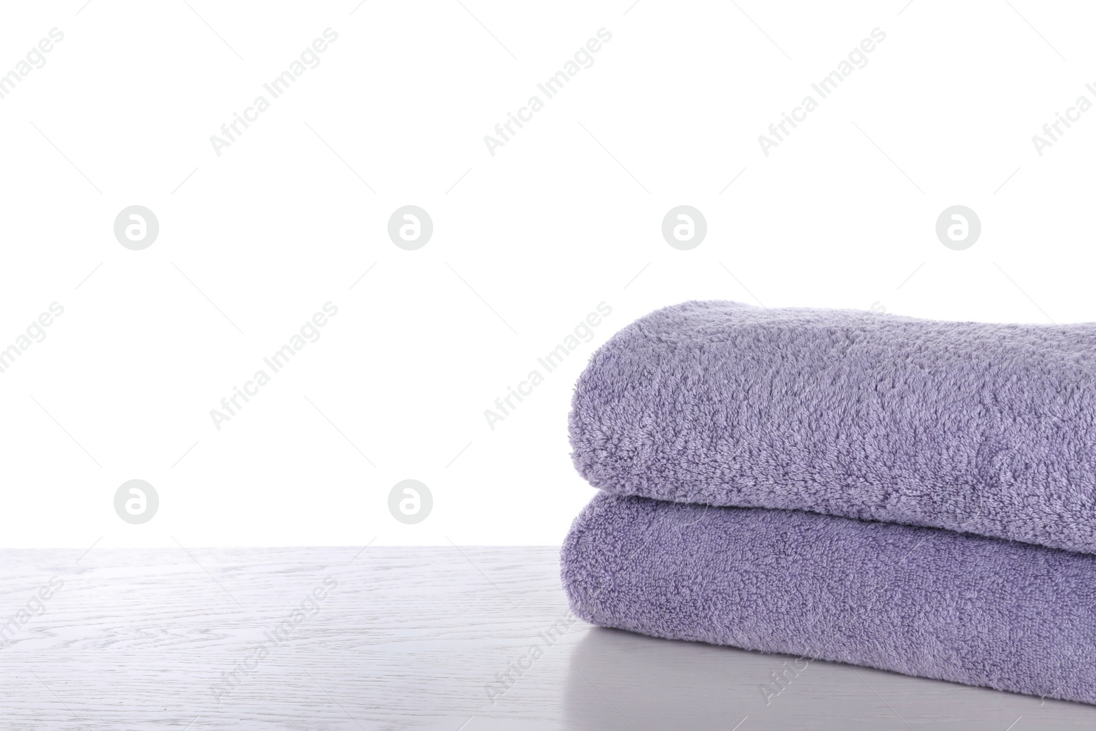 Photo of Fresh towels on wooden table against white background. Space for text