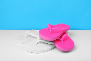 Photo of Different flip flops on white table against light blue background