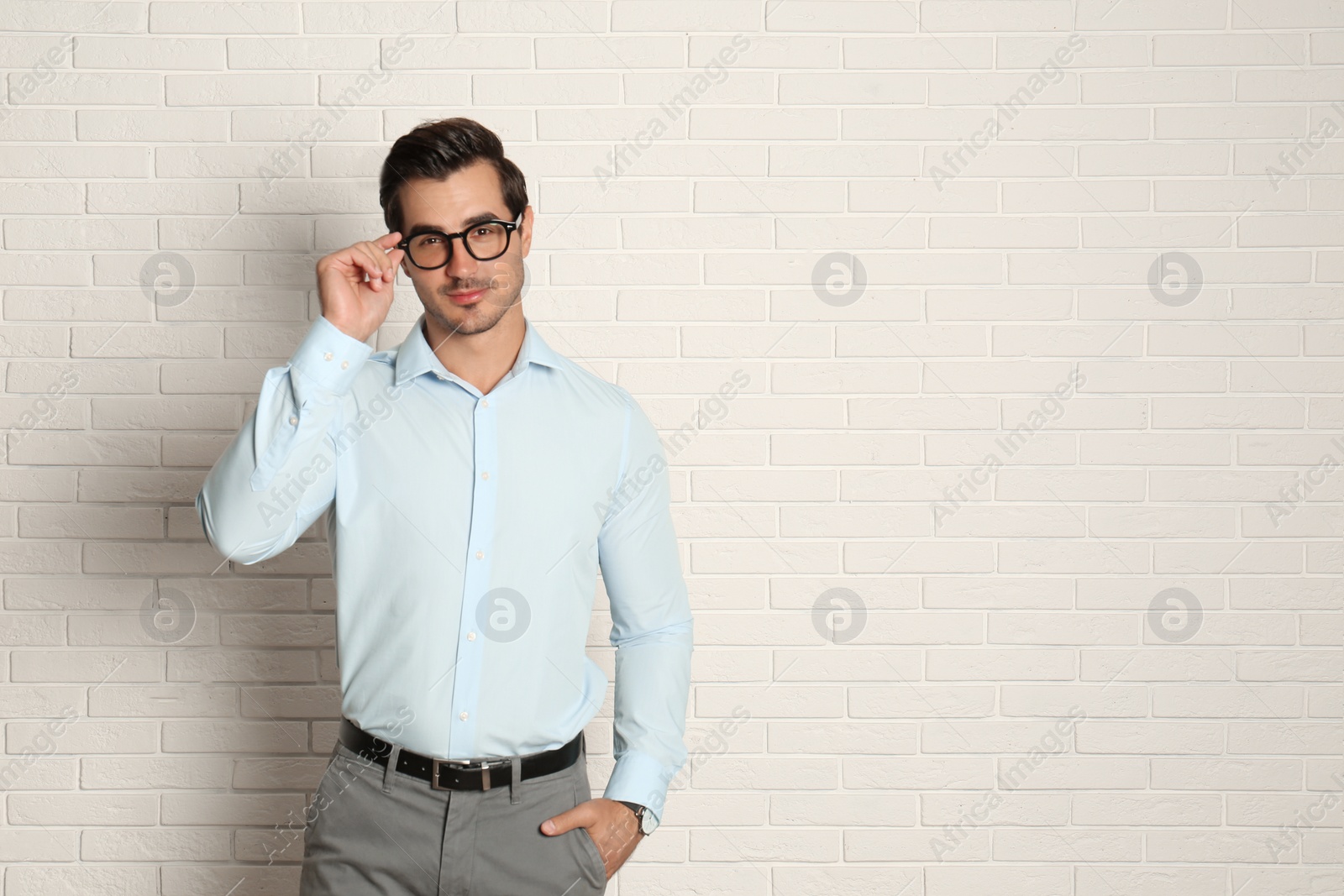 Photo of Young man with glasses near brick wall. Space for text