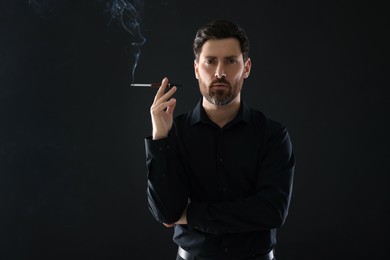 Photo of Man using cigarette holder for smoking on black background, space for text