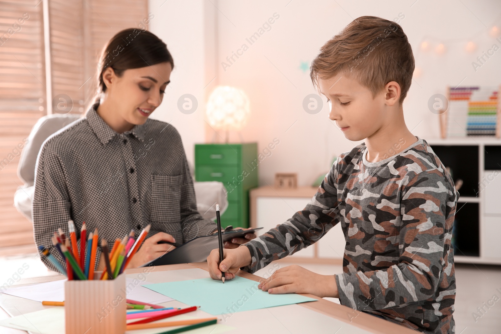 Photo of Female psychologist working with cute little boy in office