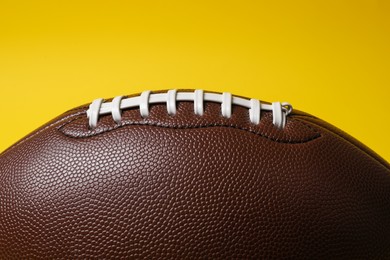 Photo of American football ball on yellow background, closeup