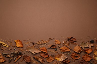 Flat lay composition with dry autumn leaves on brown background, space for text