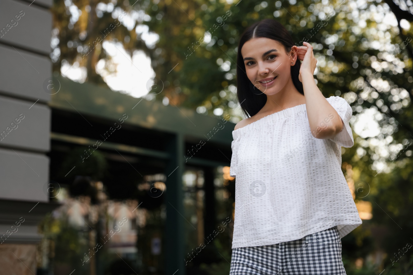 Photo of Beautiful young woman walking in green park, space for text