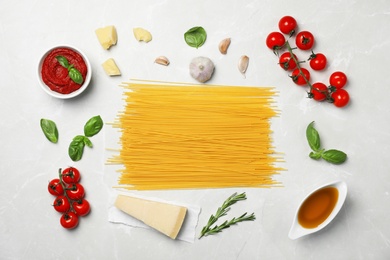 Beautiful composition with raw pasta and ingredients for sauce on table, top view