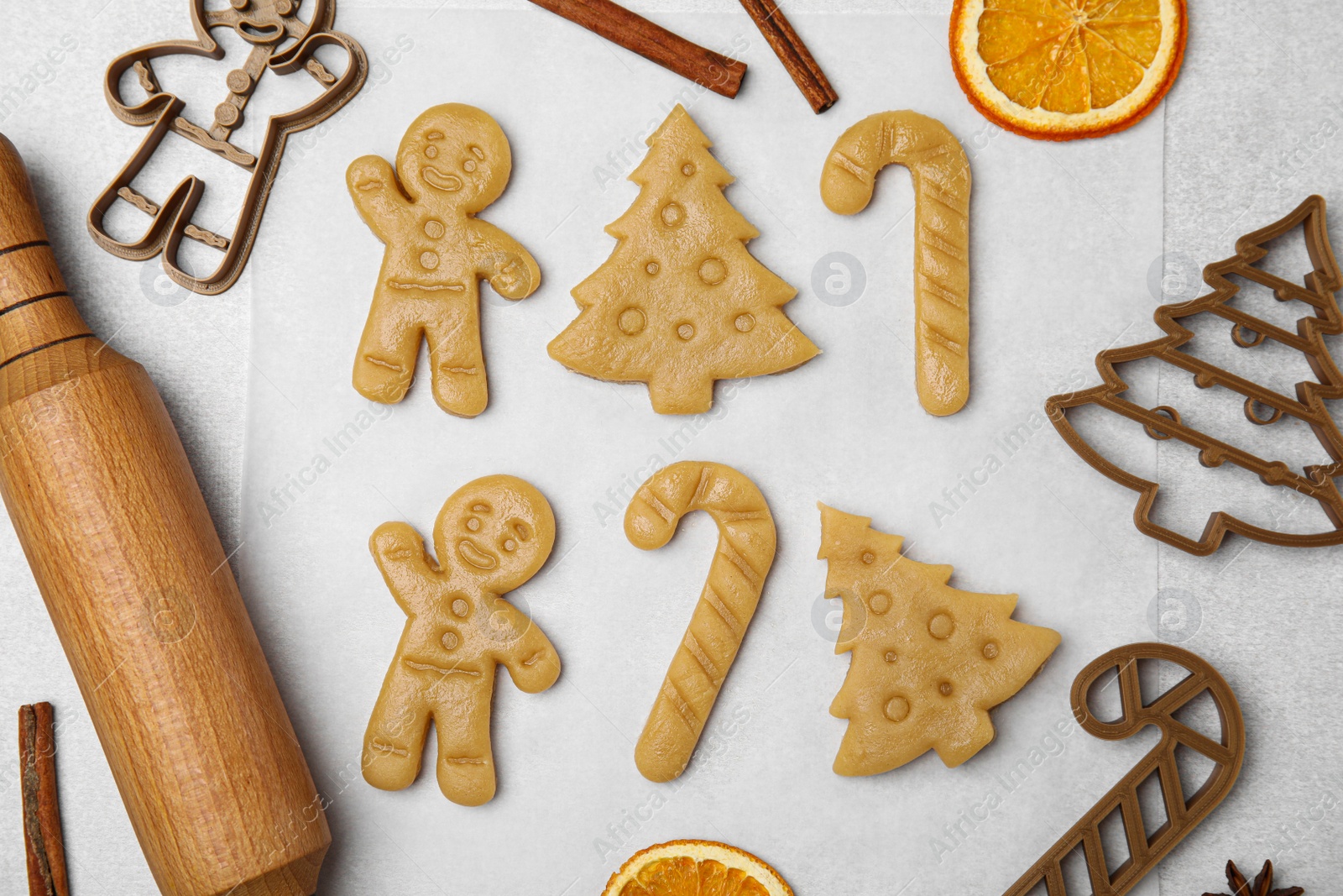 Photo of Christmas treat. Flat lay composition with cookie cutters and dough on light table