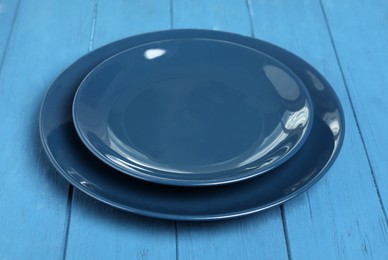 Empty clean ceramic dishware on blue wooden table, closeup