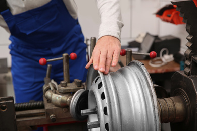 Mechanic working with car disk lathe machine at tire service, closeup