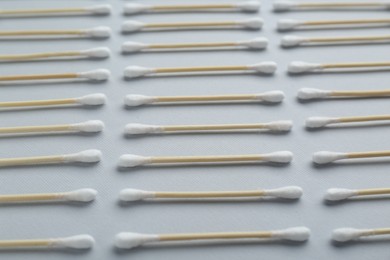 Photo of Many wooden cotton buds on light grey background, closeup