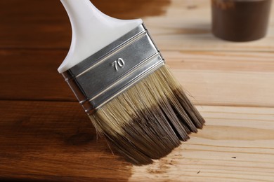 Photo of Applying wood stain with brush onto wooden surface, closeup