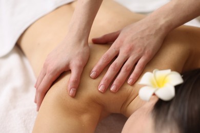 Woman receiving back massage on couch in spa salon, closeup