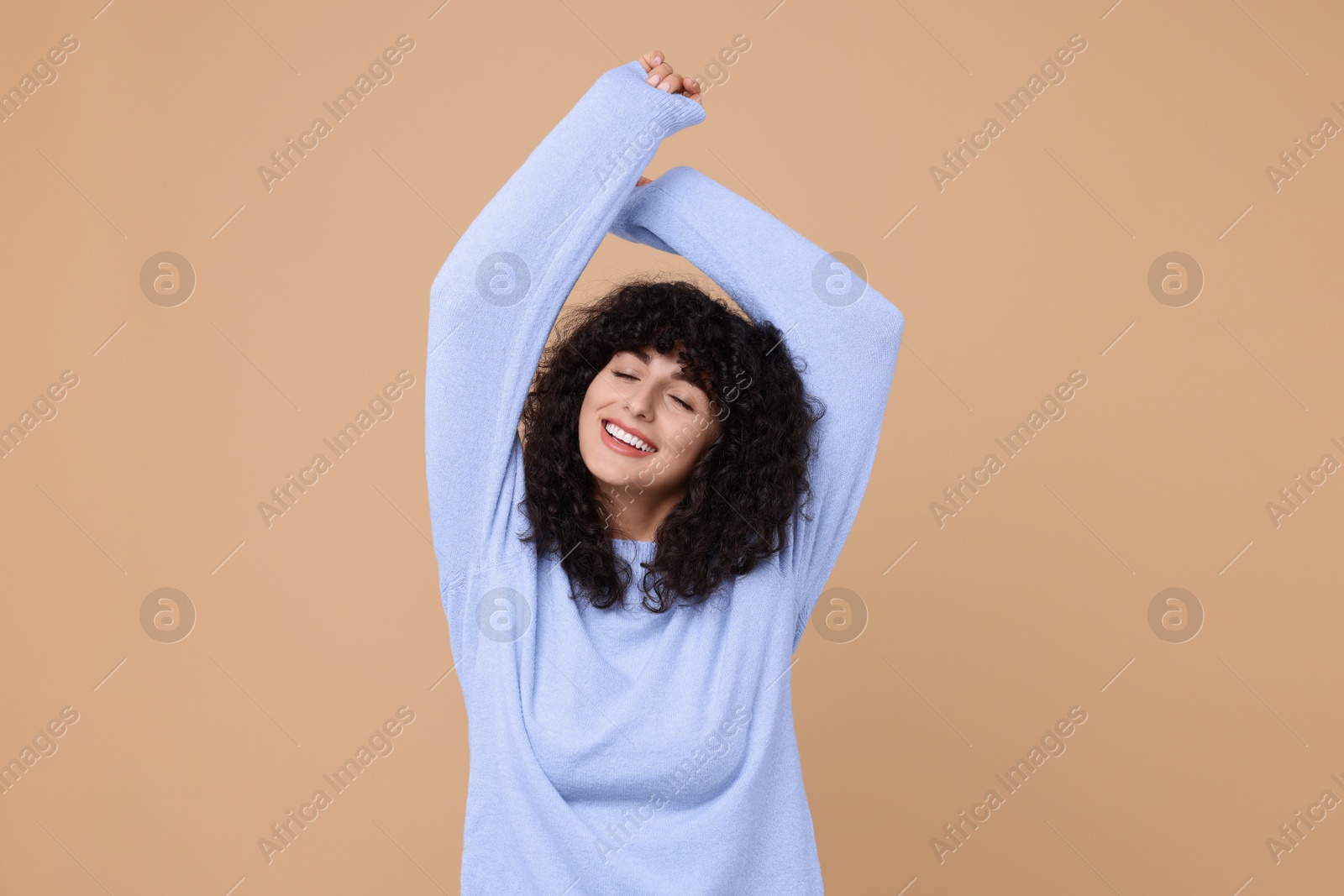 Photo of Happy young woman in stylish light blue sweater on beige background