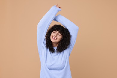 Happy young woman in stylish light blue sweater on beige background