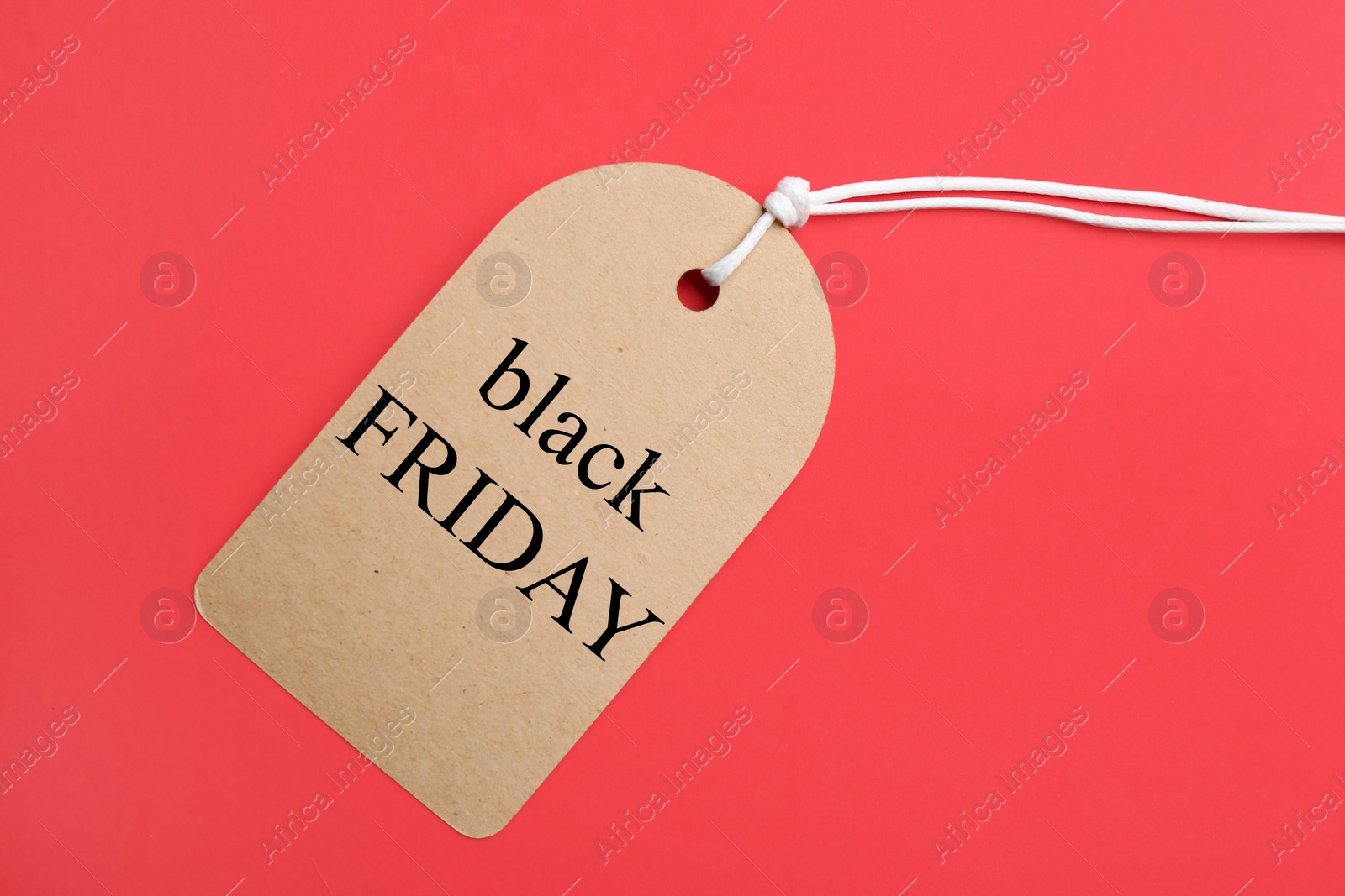 Photo of Tag with words BLACK FRIDAY on red background, top view