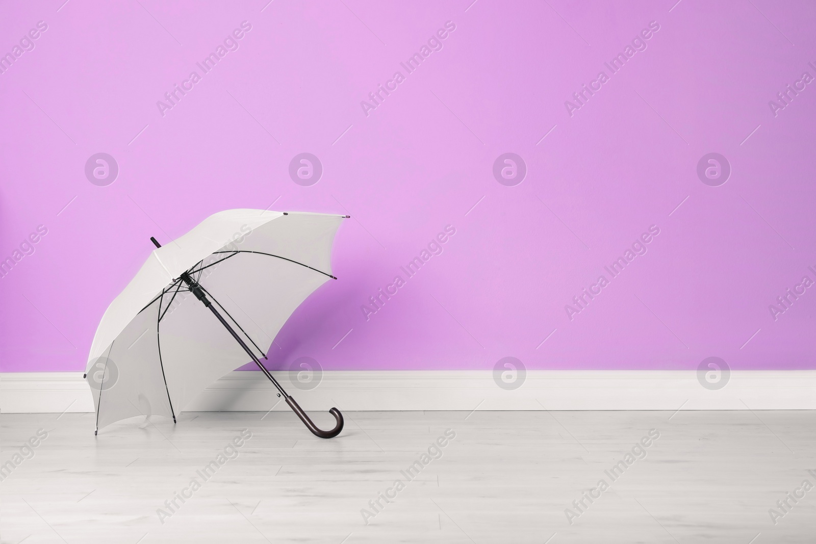 Photo of Beautiful open umbrella on floor near color wall with space for design