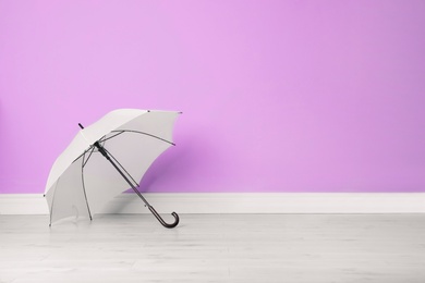 Photo of Beautiful open umbrella on floor near color wall with space for design