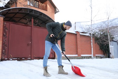 Young man shoveling snow outdoors on winter day