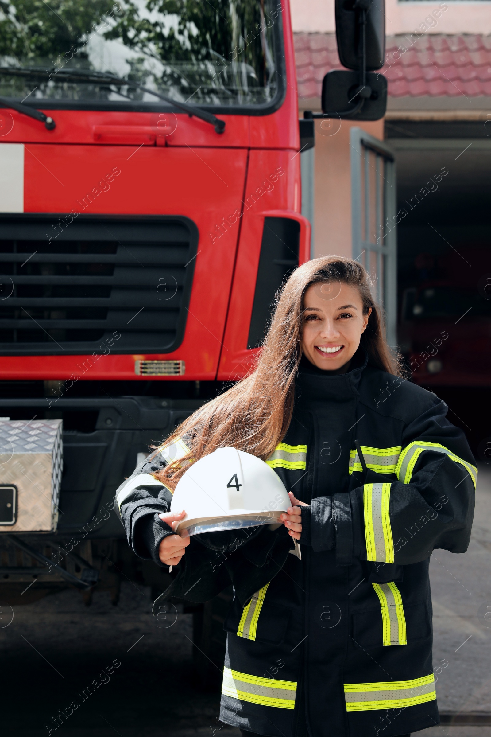 Photo of Portrait of firefighter in uniform with helmet near fire truck outdoors