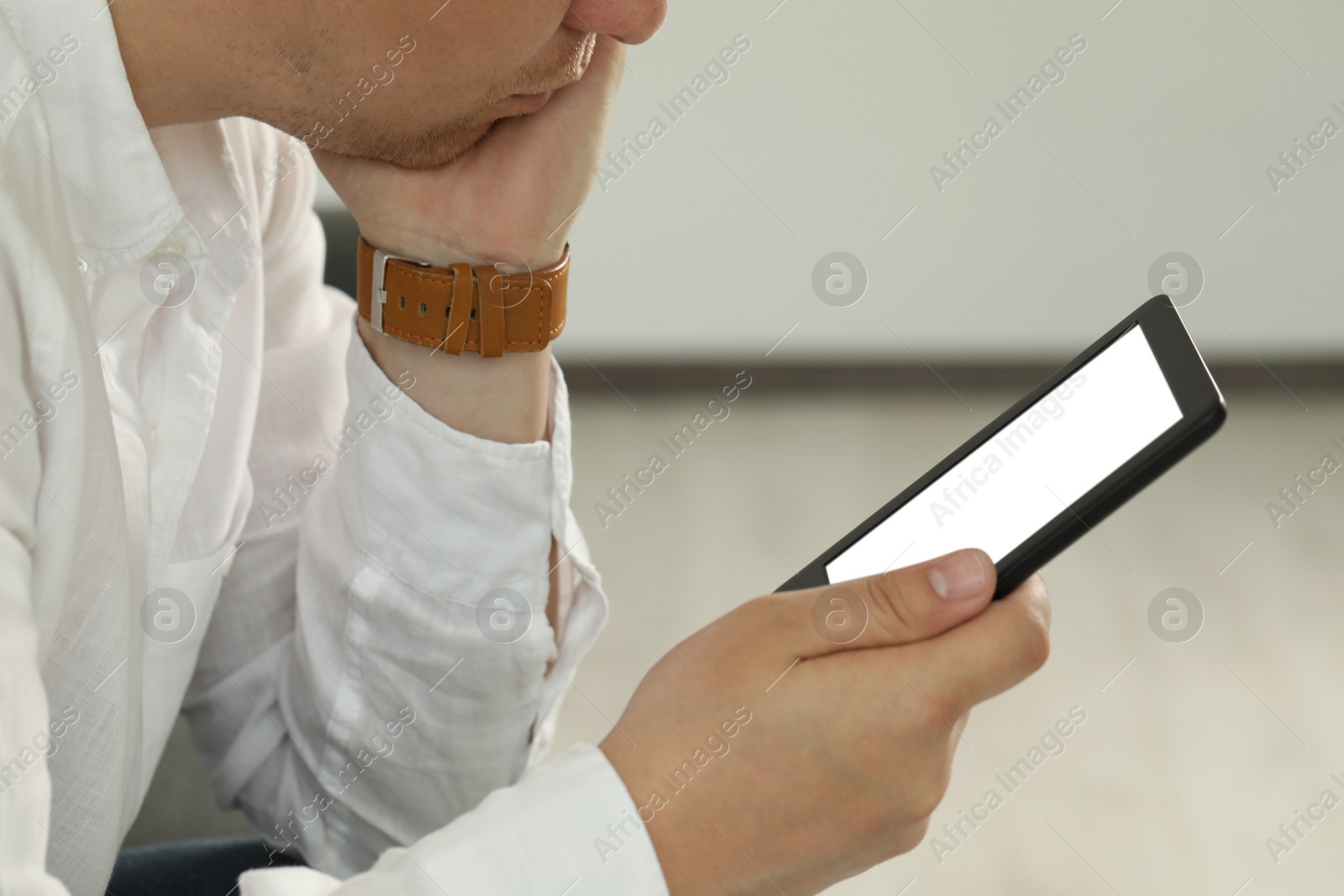 Photo of Man using e-book reader indoors, closeup view