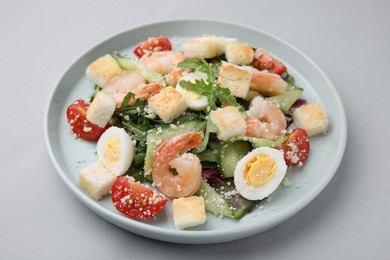 Photo of Delicious Caesar salad with shrimps on grey background, closeup