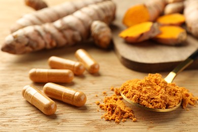 Photo of Aromatic turmeric powder and pills on wooden table, closeup