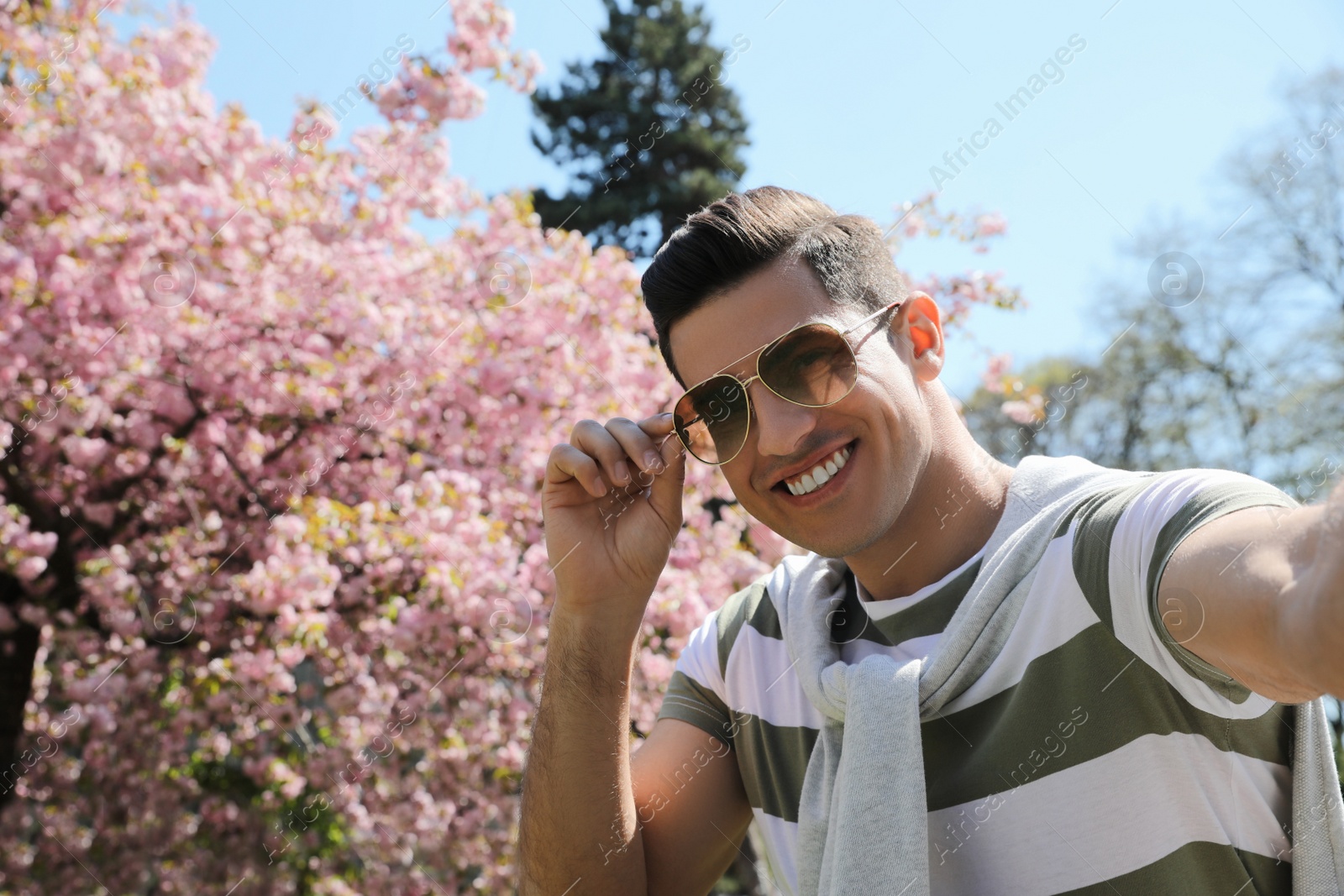 Photo of Happy handsome man taking selfie in park