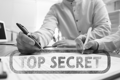 Image of Classified information. Stamp Top Secret on black and white businesspeople signing contract at table in office