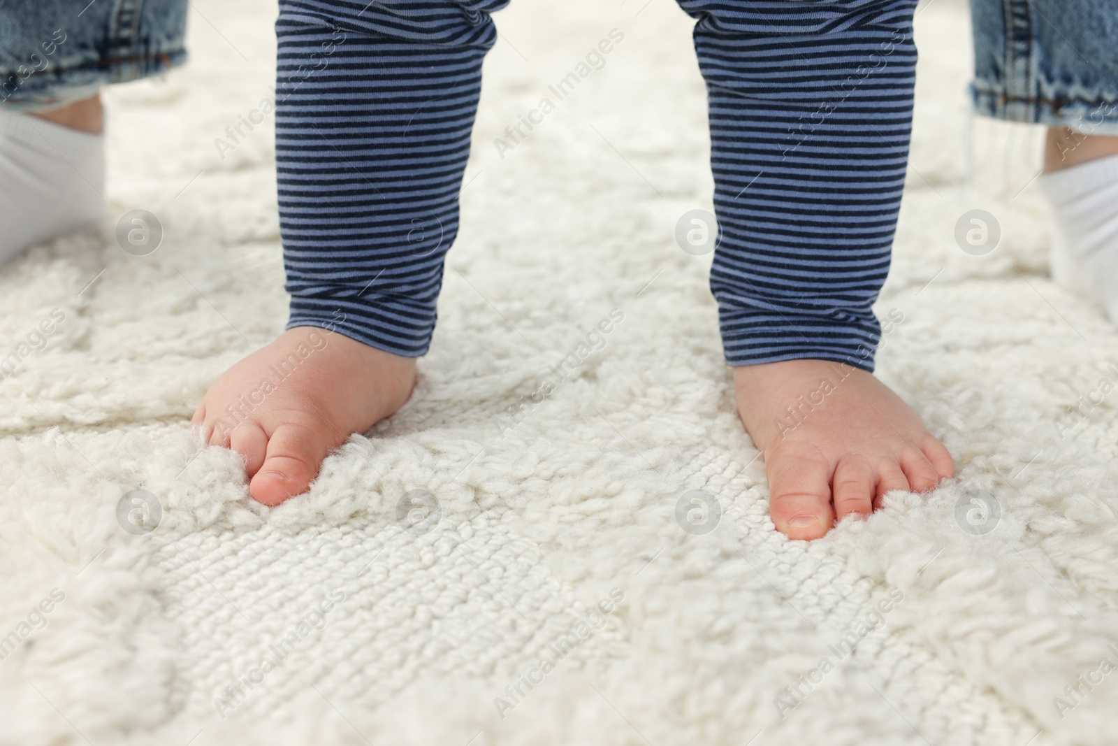 Photo of Mother and baby standing on soft carpet, closeup