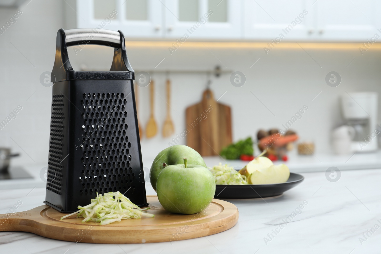 Photo of Grater and fresh ripe apples on white table in kitchen. Space for text