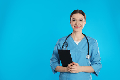 Photo of Doctor with stethoscope and clipboard on blue background. Space for text