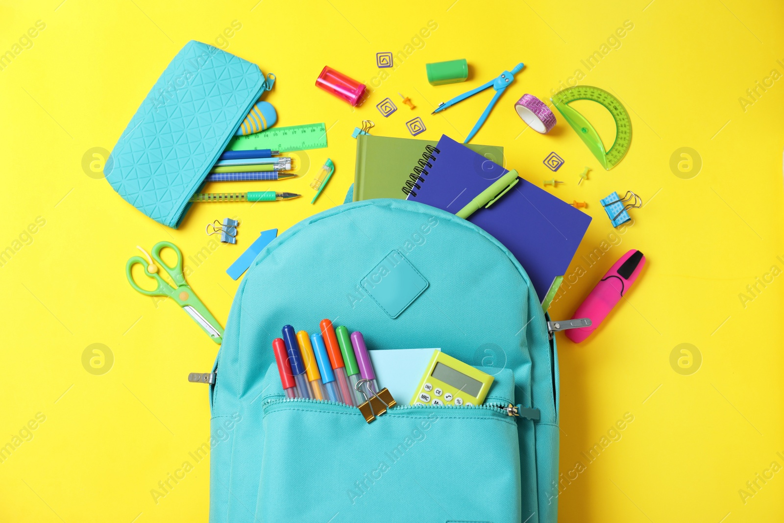 Photo of Stylish backpack with different school stationery on yellow background, flat lay