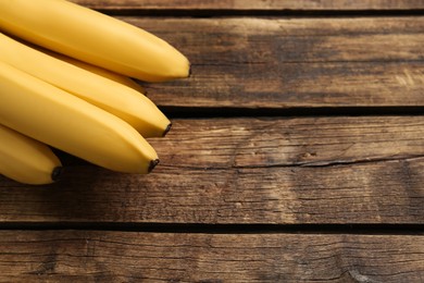 Photo of Ripe sweet yellow bananas on wooden table. Space for text