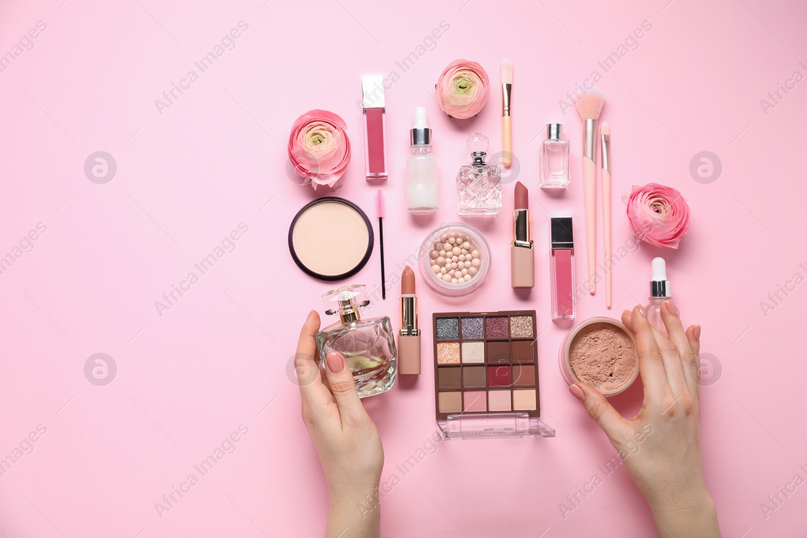 Photo of Woman with different makeup products and beautiful spring flowers on pink background, top view. Space for text