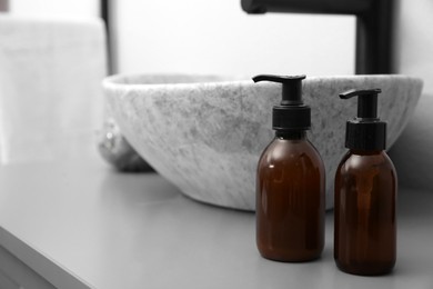 Photo of Dispensers of liquid soap near sink in bathroom. Space for text