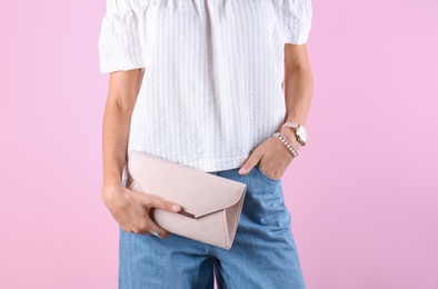 Young woman in stylish outfit with purse on color background, closeup