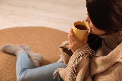 Young woman with cup of tea relaxing on floor at home, closeup. Space for text