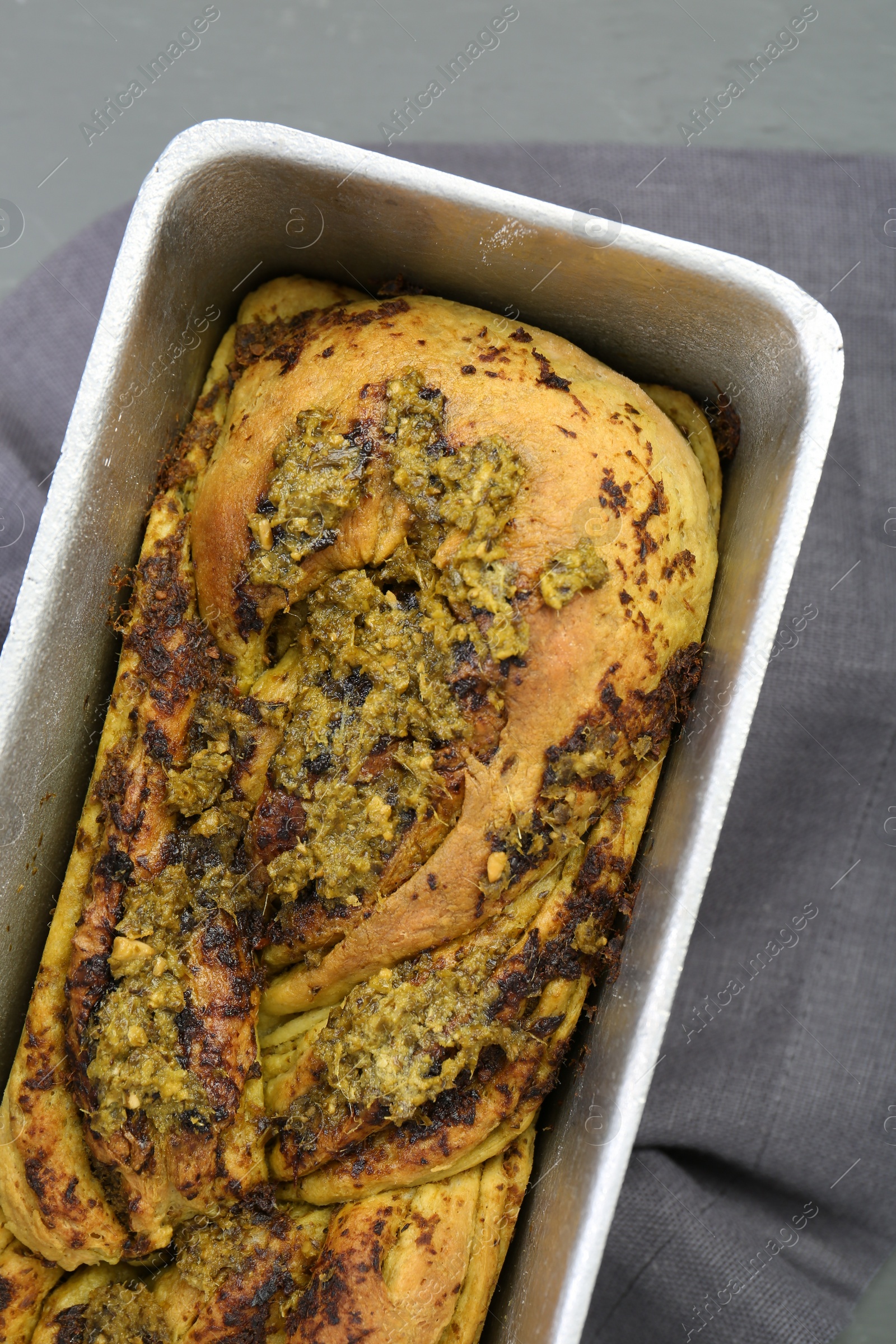 Photo of Freshly baked pesto bread in loaf pan on table, top view