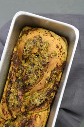 Photo of Freshly baked pesto bread in loaf pan on table, top view