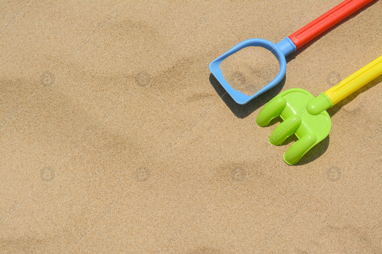 Photo of Plastic shovel and rake on sand, space for text. Beach toys