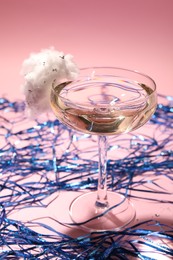 Photo of Tasty cocktail in glass decorated with cotton candy and blue shiny streamers on pink background